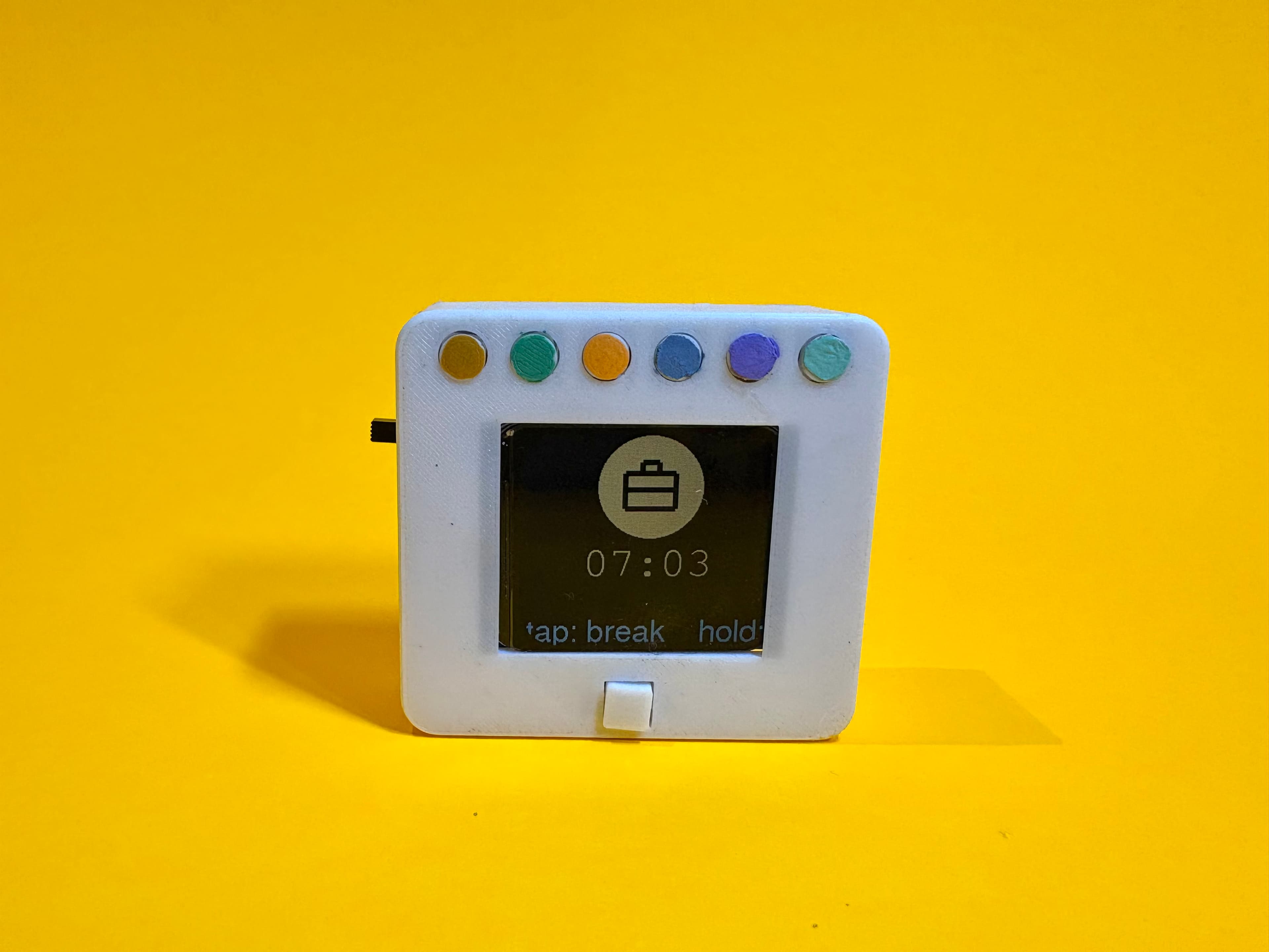 The Acra Pocket prototype on a yellow background, showing a work session at 07:03